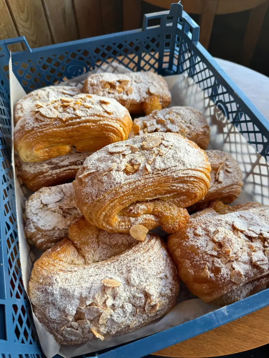 Croissants almon wedi’u pobi’n ffres mewn crât o’r popty lleol